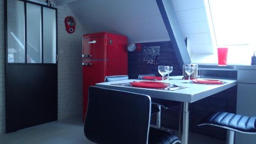 uma cozinha com um frigorífico vermelho e uma mesa com copos de vinho em La louisiane em Montivilliers