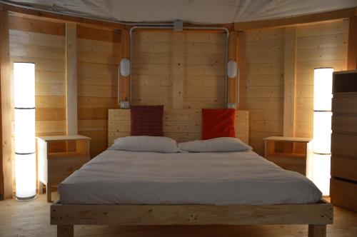 a large bed in a wooden room with two lamps at Camping Du Parc in Pré-Saint-Didier