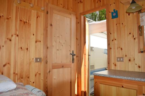 baño con pared de madera y puerta en Camping Du Parc, en Pré-Saint-Didier