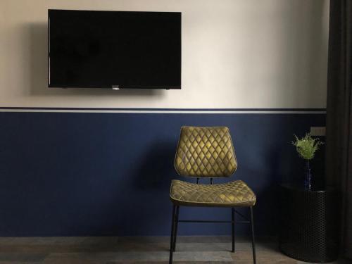 a chair sitting in front of a blue wall with a television at Goodnight Poshtel + Free Netflix in Hat Yai