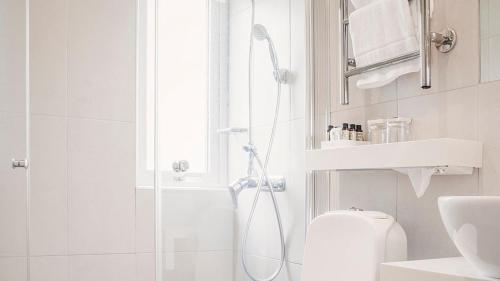 a white bathroom with a shower and a toilet at Hotel Tylösand in Tylösand