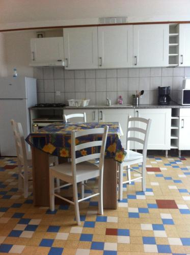 une cuisine avec une table et des chaises et une cuisine avec des armoires blanches dans l'établissement La Prunelle 1, à Ferrières-Saint-Mary