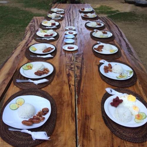 a long wooden table with plates of food on it at White Beach Front and Cottages in Buruanga