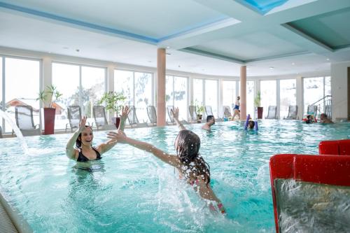 dos personas jugando en una piscina en Heidi-Hotel Falkertsee - Kinderhotel, en Patergassen