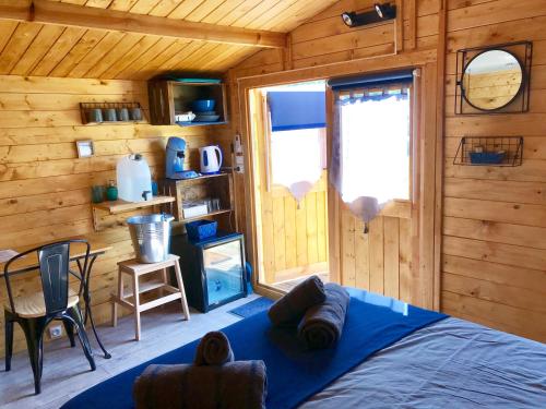 ein Schlafzimmer mit einem blauen Bett in einer Holzhütte in der Unterkunft Locations insolites "vie en plein air" cabane et tipi Bastide Bellugue maison d'hôtes reseau Bienvenue à la ferme à 3 mn de lourmarin in Cadenet
