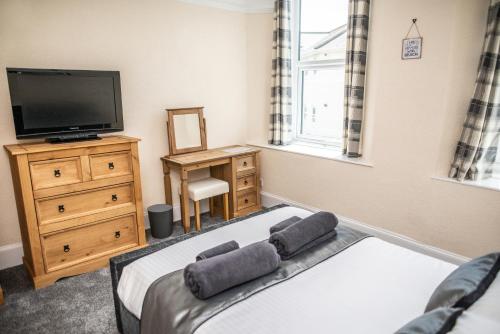 een slaapkamer met een bed, een televisie en een dressoir bij Babbacombe Apartments in Torquay