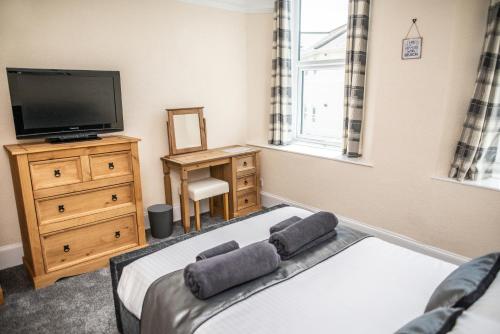 sypialnia z łóżkiem, telewizorem i komodą w obiekcie Babbacombe Apartments w mieście Torquay