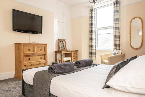 een slaapkamer met een bed en een tv aan de muur bij Babbacombe Apartments in Torquay