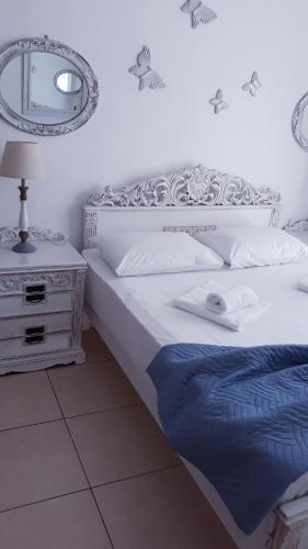 a white bedroom with a bed and a mirror at Christos Rooms in Palaiochóra