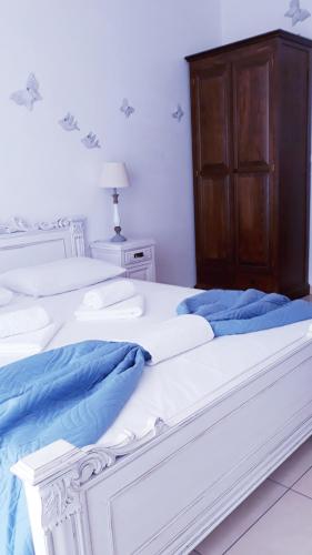 two white beds with blue sheets and a wooden cabinet at Christos Rooms in Palaiochóra