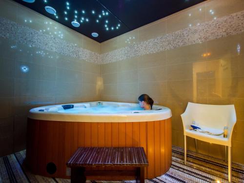 a woman sitting in a hot tub in a room at Hotel Krystal in Luhačovice