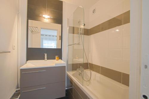 een badkamer met een wastafel, een spiegel en een bad bij APPARTEMENT MODERNE A CAEN POUR 4 PERSONNES in Caen