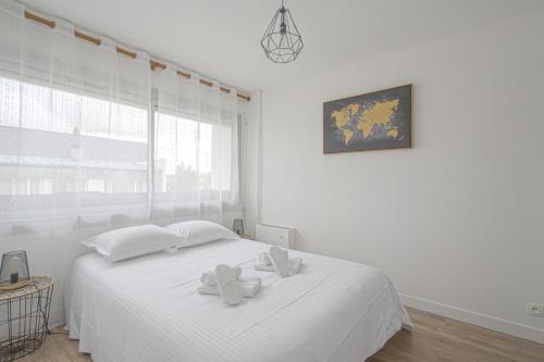 biała sypialnia z białym łóżkiem i 2 białymi ręcznikami w obiekcie APPARTEMENT MODERNE A CAEN POUR 4 PERSONNES w Caen
