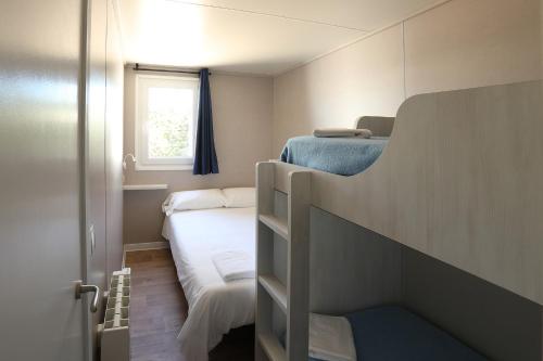 Dormitorio pequeño con litera y ventana en Camping Bayona Playa, en Sabaris