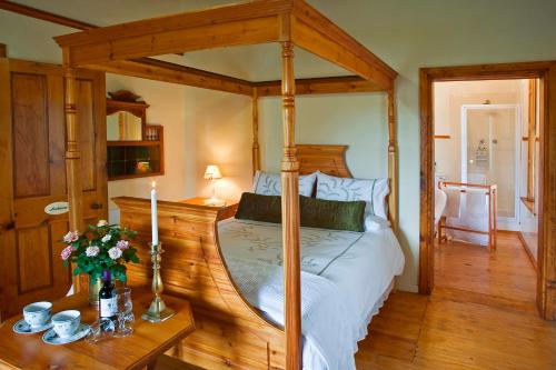ein Schlafzimmer mit einem Himmelbett und einem Holzboden in der Unterkunft Centre-Ville Guest House in Franschhoek