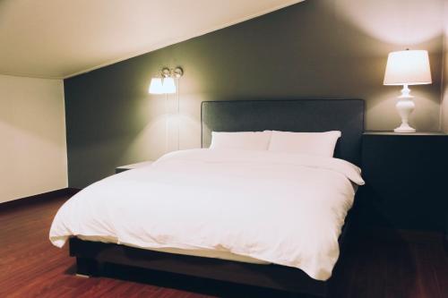 a bedroom with a large white bed and two lamps at GONGGAN Residence Hotel in Geoje 