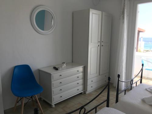 a bedroom with a dresser and a blue chair at Danaides Studios in Batsi