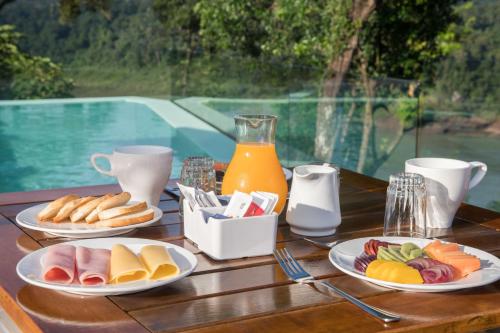 a wooden table with plates of food and orange juice at Tupa Lodge in Puerto Iguazú