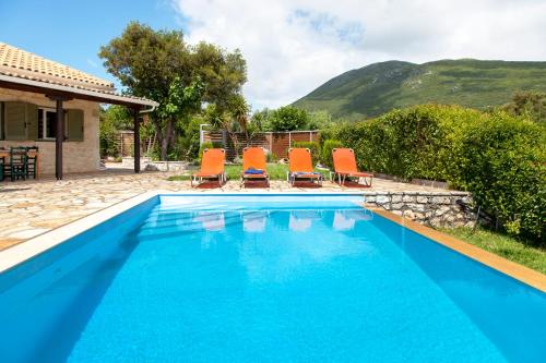 a swimming pool with orange chairs and a house at Villa Melody Private Pool Villa with Mountain Views in Fternón