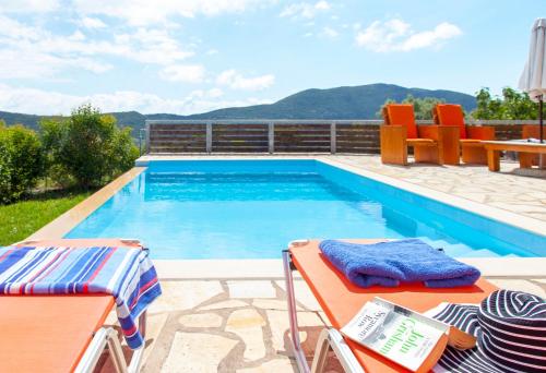 a swimming pool with two chairs and a table next to it at Villa Melody Private Pool Villa with Mountain Views in Fternón