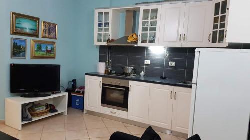 a kitchen with white cabinets and a tv in it at Bonbon Sea Apartment in Orikum
