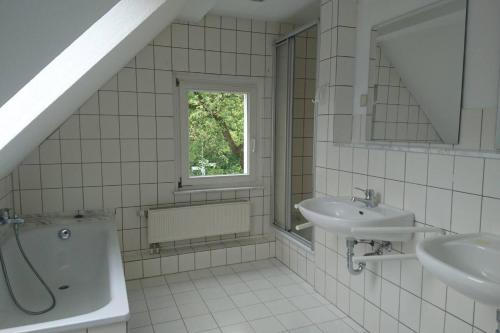 łazienka z 2 umywalkami, wanną i oknem w obiekcie Sonniges Häuschen mit Garten w Brunszwiku