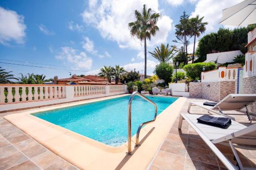 a swimming pool in a villa with palm trees at Villa Mirador for a great holiday - by Holiday Rentals Villamar in Benissa