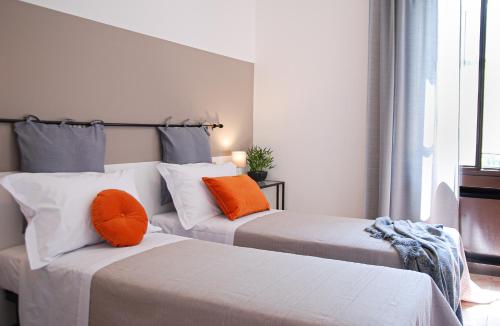 two beds with orange pillows in a room at Home & Pet - Fiori in Basiglio