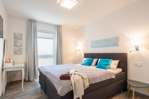 Un dormitorio con una cama con almohadas azules y una ventana en Appartement "Dünentraum" - Oase am Haff, en Garz