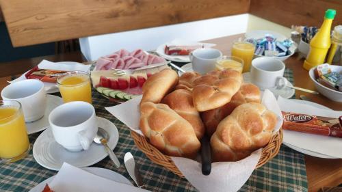 a table with a basket of bread and orange juice at Pension Aspen Harrachov in Harrachov