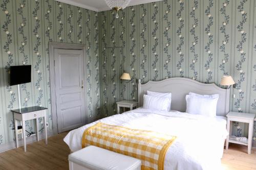 a bedroom with a bed with green and white wallpaper at Thottska Villan in Strömsholm