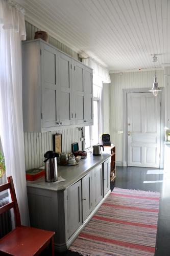 a kitchen with white cabinets and a table with a rug at Thottska Villan in Strömsholm