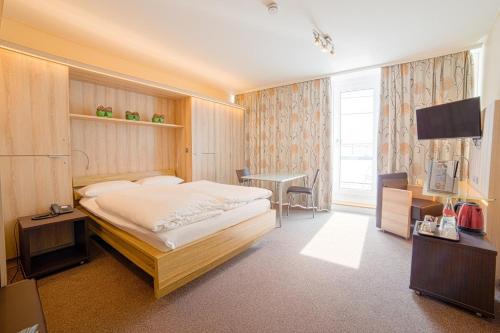 a bedroom with a bed and a desk and a television at City Hotel Hannover in Hannover