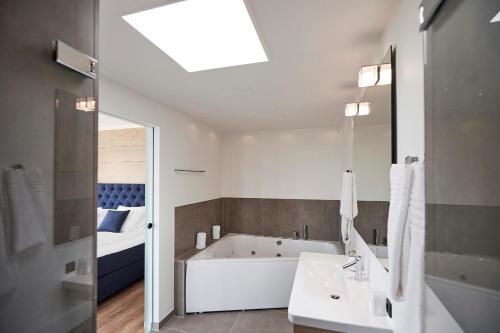a bathroom with a tub and a sink and a bed at Hotel Skjern in Skjern
