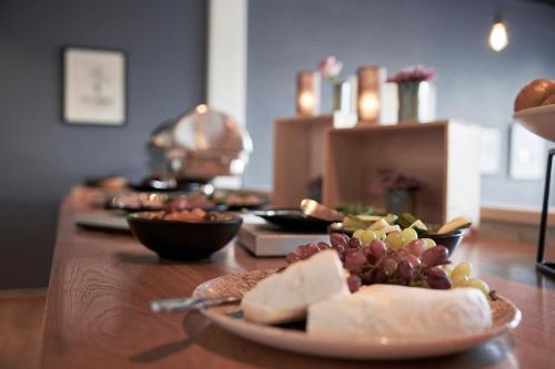 a wooden table with a plate of cheese and grapes at Hotel Skjern in Skjern
