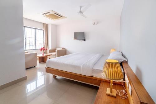 a bedroom with a bed and a table with a lamp at Hotel BKM International in Tellicherry