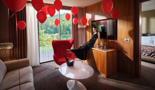 a woman sitting in a red chair in a room with red balloons at Atlantida Boutique Hotel in Rogaška Slatina