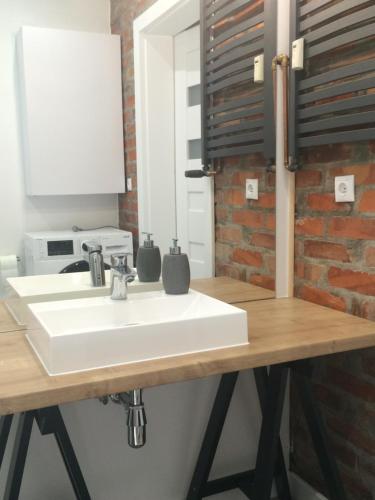 a bathroom with a white sink and a brick wall at Apartament Lila in Świnoujście