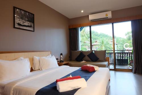 a hotel room with two beds and a couch at Koh Ma Beach Resort - SHA Extra Plus in Mae Haad