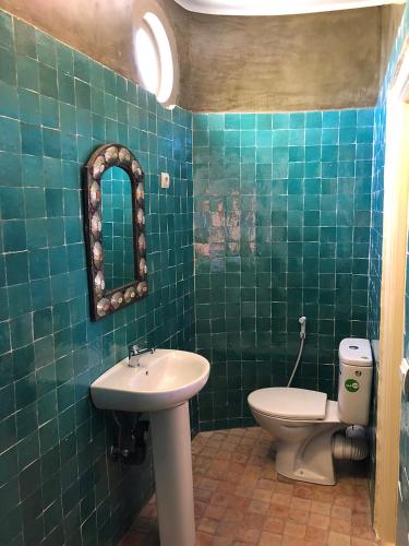 a green tiled bathroom with a sink and a toilet at Ryad 91 in Casablanca