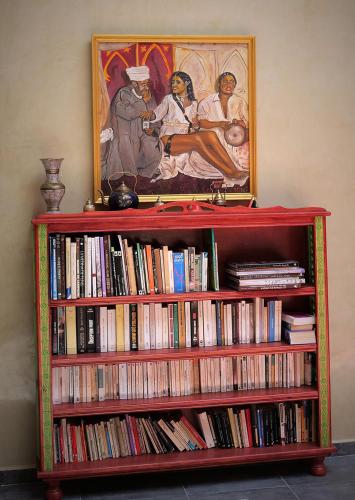 a book shelf full of books with a painting on the wall at Ryad 91 in Casablanca