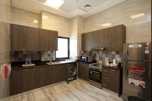 a large kitchen with wooden cabinets and a refrigerator at Marbella Holiday Homes in Dubai