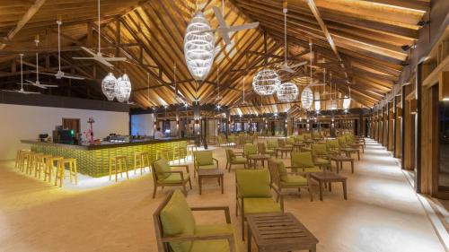 Cette grande chambre comprend des chaises, des tables et des lustres. dans l'établissement Innahura Maldives Resort, à Lhaviyani Atoll