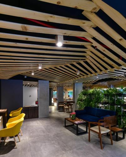 a living room with a blue couch and yellow chairs at Hotel Centro in Pune
