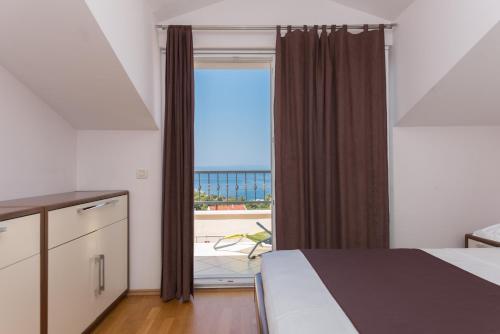 1 dormitorio con cama y vistas al océano en Apartments Naja, en Makarska