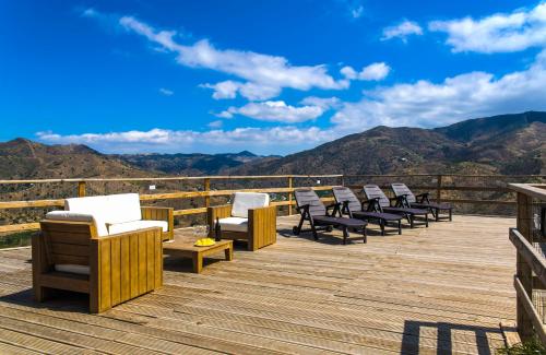 a deck with chairs and a view of the mountains at Complejo Rural El Mirador in Málaga