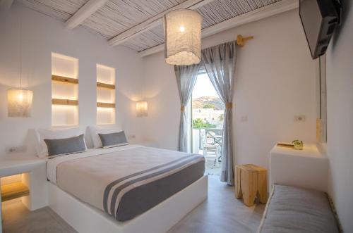 a white bedroom with a bed and a window at Yialos Ios Hotel in Ios Chora