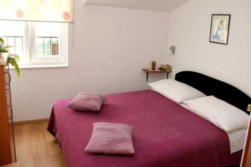 sypialnia z fioletowym łóżkiem z 2 poduszkami w obiekcie Apartment Bucevic w Szybeniku