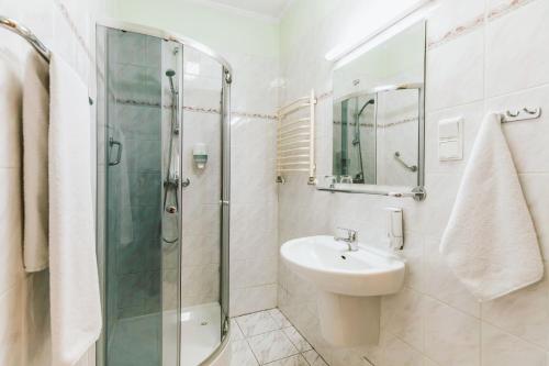een witte badkamer met een wastafel en een douche bij Hotel Gromada Toruń in Toruń