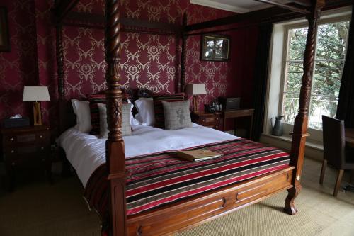 a bedroom with a canopy bed with a book on it at The Museum Inn in Farnham